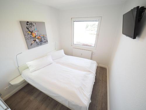 ein kleines Schlafzimmer mit einem weißen Bett und einem Fenster in der Unterkunft Appartement 206 in Westerland