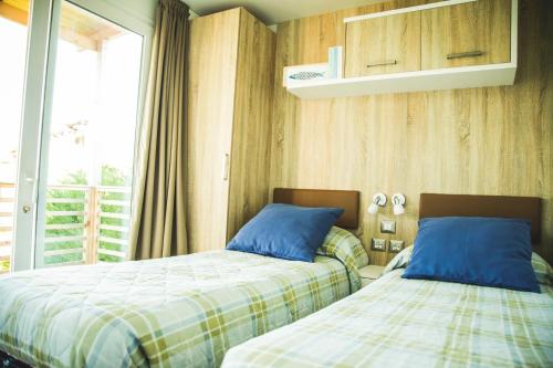Duas camas sentadas uma ao lado da outra num quarto em Camping Vallecrosia em Vallecrosia