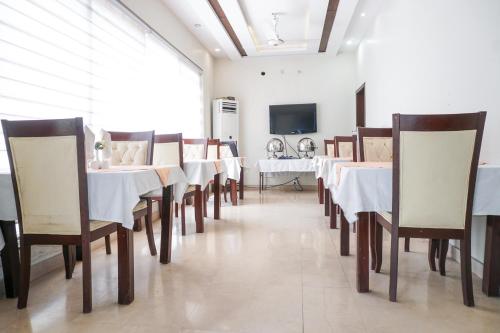 uma sala de jantar com mesas e cadeiras e uma televisão em City View Hotel & Restaurant em Lahore
