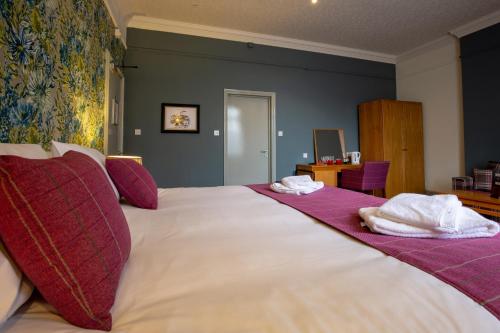 a bedroom with a large white bed with purple pillows at Woodthorpe Hotel in Manchester