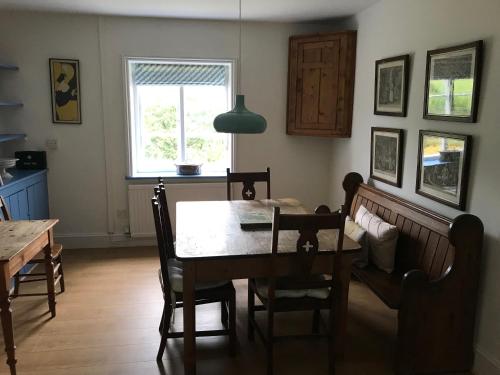 ein Esszimmer mit einem Tisch, Stühlen und einem Fenster in der Unterkunft Owlpen Manor Cottages in Uley