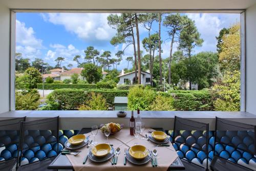 une table dans un restaurant avec une grande fenêtre dans l'établissement Appartement Pyla Les Cèdres, à Pyla-sur-Mer