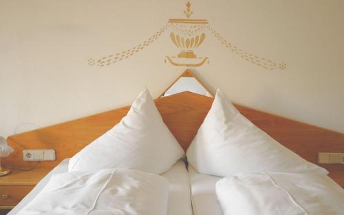 a bed with white sheets and pillows on it at Hotel Pfleger in Anras