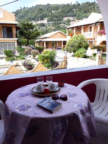 a table with glasses on it with a view of a balcony at MARGARITAS' ROOMS in Agios Gordios