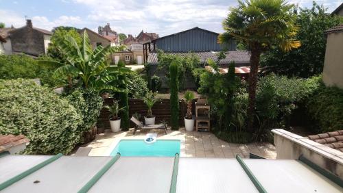 a backyard with a swimming pool and palm trees at Le patio d'olivier in Lalinde