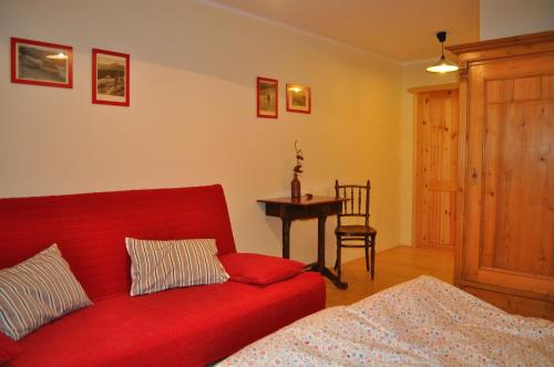 a living room with a red couch and a table at Horská chalupa U Hančilů in Pec pod Sněžkou