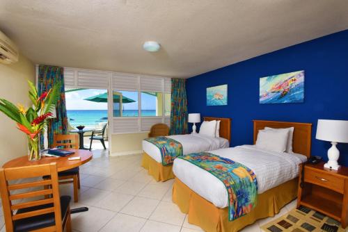 a hotel room with two beds and a view of the ocean at Coral Mist Beach Hotel in Bridgetown