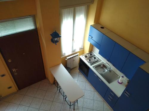 kuchnia z niebieskimi szafkami, kuchenką i oknem w obiekcie Casa vacanze IL VIOLINO w mieście Cremona