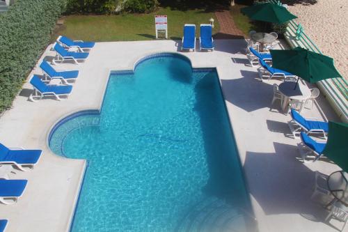 a swimming pool with blue chairs and umbrellas at Coral Mist Beach Hotel in Bridgetown