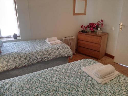 a bedroom with two beds and a dresser with flowers at Le Chene Vert in Millac