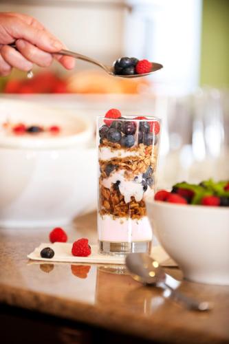 a person is eating granola with berries and a bowl of fruit at Country Inn & Suites by Radisson, Tulsa, OK in Tulsa