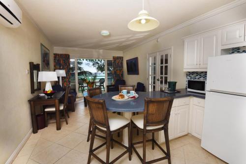 a kitchen with a table and chairs and a refrigerator at Coral Mist Beach Hotel in Bridgetown
