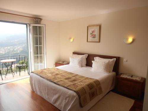 a bedroom with a large bed and a balcony at Refúgio das Camélias in Santana