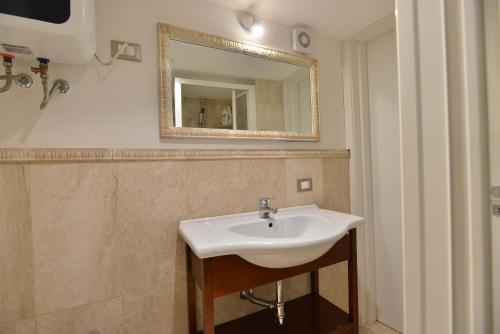 a bathroom with a white sink and a mirror at IzzHome City Center Cozy in Cagliari