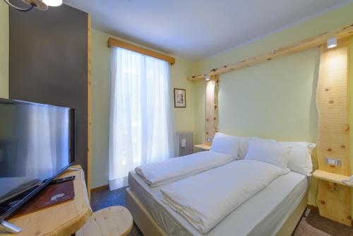 a bedroom with a bed and a flat screen tv at Park Hotel Faloria in Canazei