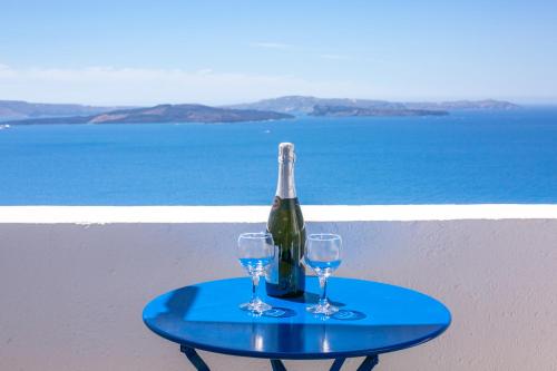 a bottle of wine and two glasses on a table at Stelios Rooms in Oia