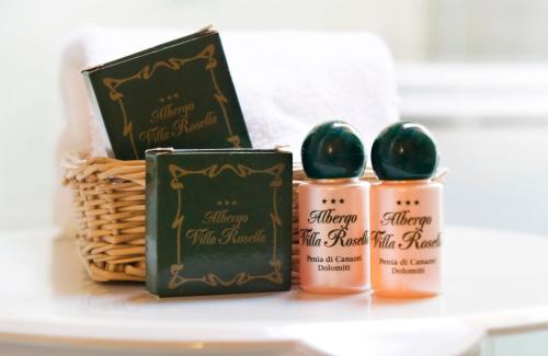 a shelf with three candles and a basket of cosmetics at Hotel Villa Rosella Park & Wellness in Canazei