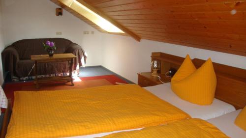 a bedroom with a bed with a yellow blanket and a chair at Mettenberger Hof - Pension in Grafenhausen
