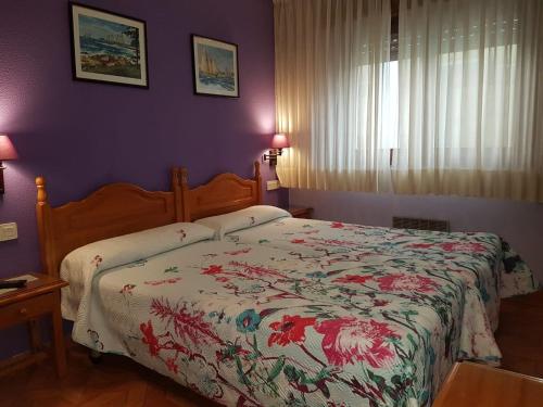 1 dormitorio con 1 cama con colcha de flores en Pensión El Camarote, en Cudillero