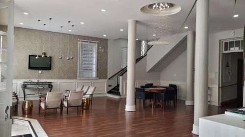 a living room with a staircase and a table and chairs at MOVA Hotel D'oeste - Localizado em frente a Praça Principal da Cidade, na área Central - Pé na Praça in Poços de Caldas