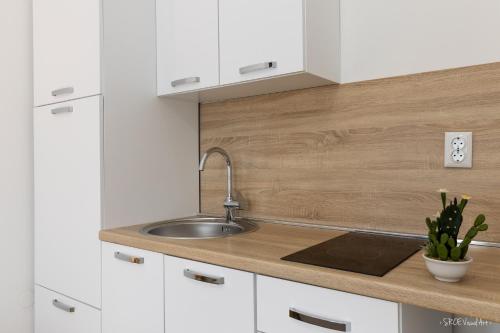 a kitchen with white cabinets and a sink at Apartmani Gundulić in Osijek