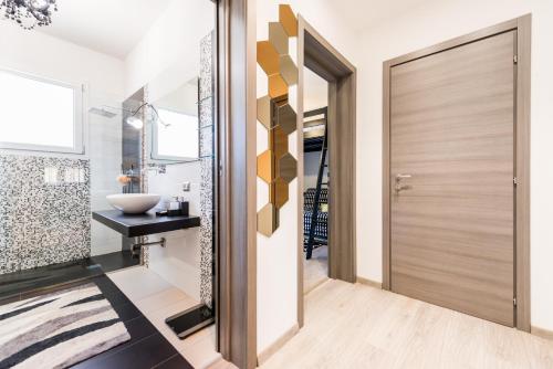 a bathroom with a wooden door and a sink at Uliveto' s Apartment in Elmas