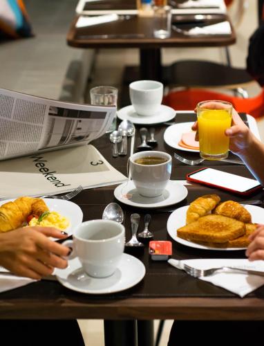 a table with plates of food and cups of coffee at ibis Sao Bernardo do Campo in São Bernardo do Campo