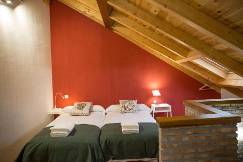 a bedroom with two beds in a red wall at Los Acebos in Horcajuelo de la Sierra