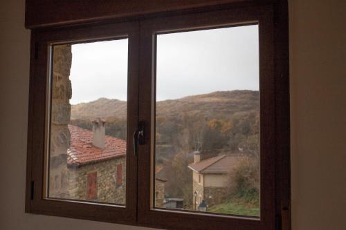 a window with a view of a house and mountains at Los Acebos in Horcajuelo de la Sierra