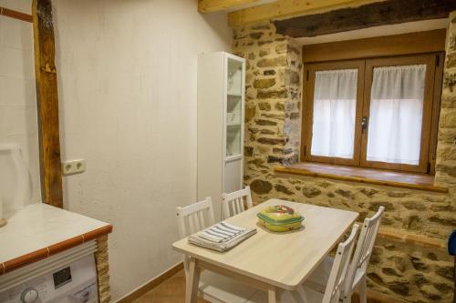 a kitchen with a white table and chairs in a room at Los Acebos in Horcajuelo de la Sierra