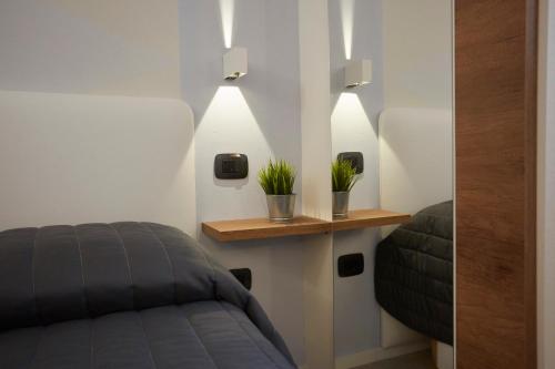 a room with a bed and two plants on a shelf at Affittacamere Somnium in Sirolo