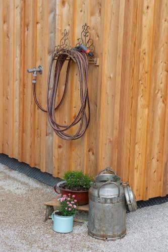 a hose hooked up to a wooden fence with a pot and plants at Chalet 164 in Bad Goisern