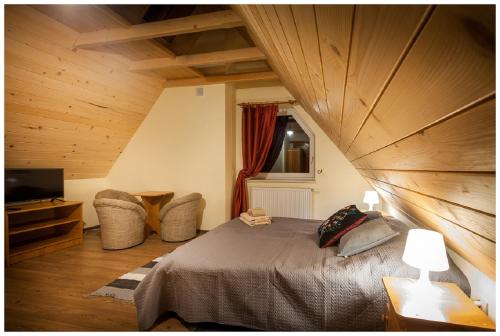 a bedroom with a large bed and a television at Tatrzańska Kotwica in Witów