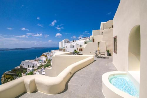 a view of the ocean from a hotel balcony with a hot tub at Aloia Villas in Oia