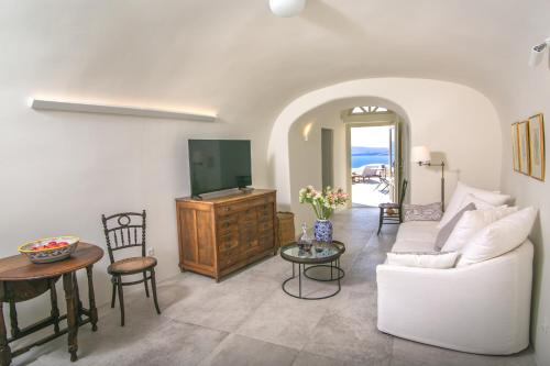 a living room with a white couch and a table at Aloia Villas in Oia