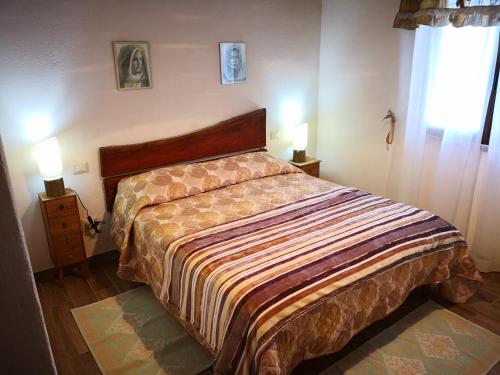Ce lit se trouve dans une chambre dotée de 2 lampes murales. dans l'établissement Villa Sa Pruna, à Oliena