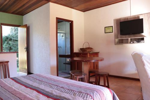 a bedroom with a bed and a table and a television at Chalé Recanto do Sossego in Gonçalves