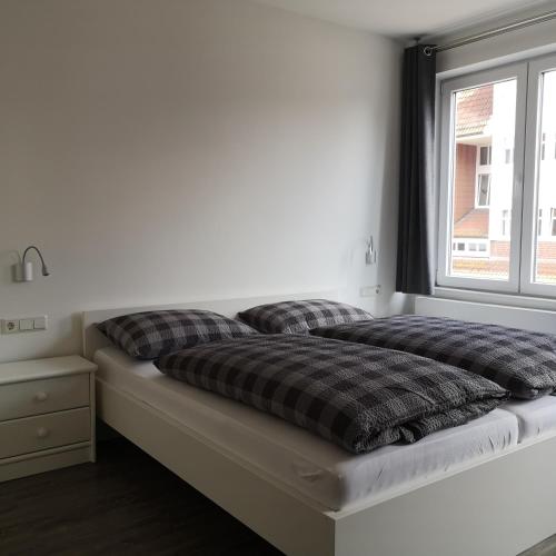 a bed with pillows on it in a room with a window at Haus Worch in Juist