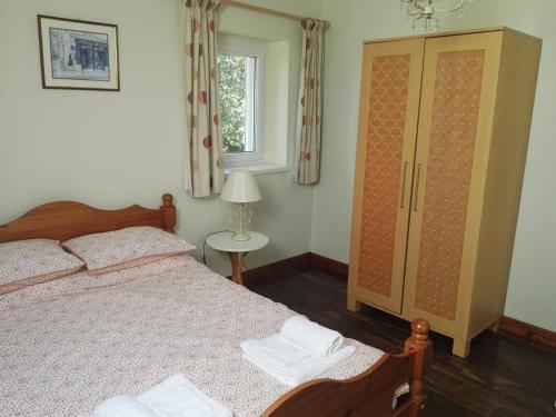 a bedroom with a bed and a cabinet and a window at Le Chene Vert in Millac