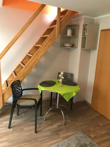 a green table and chairs in a room with stairs at Gästewohnung Saaleblick in Weißenfels