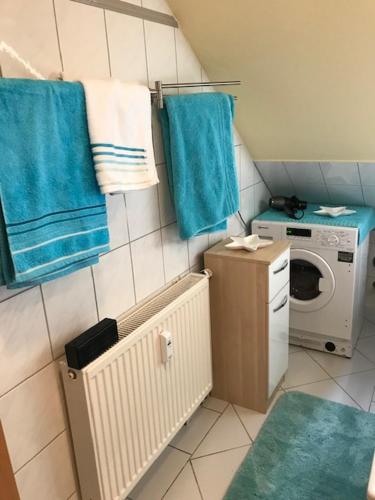a small bathroom with a washing machine and blue towels at Gästewohnung Saaleblick in Weißenfels