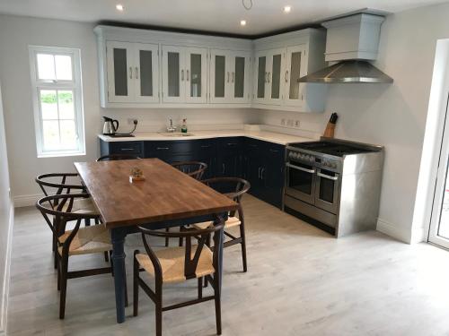 uma cozinha com uma mesa de madeira e uma cozinha com um fogão em Mary Ann's Ballyheigue Cottage em Tralee