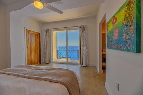 a bedroom with a bed and a view of the ocean at Villa Topaz Above West Bay with 360 Degree Views! in West Bay