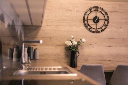 a table with a vase of flowers and a clock at Trio Tatry in Smokovce