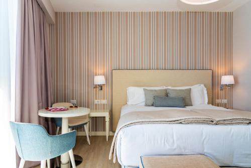 a bedroom with a bed and a table and a chair at Hotel Plaza in Porto Azzurro