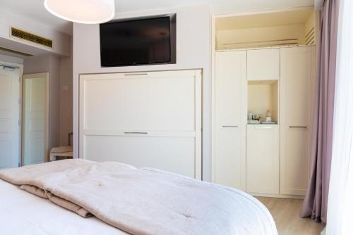 a bedroom with a bed with a tv on the wall at Hotel Plaza in Porto Azzurro