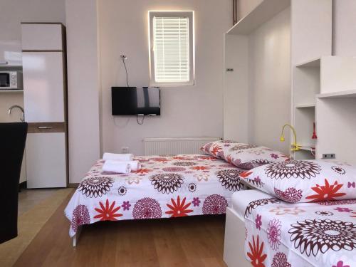 a bedroom with two beds and a tv on the wall at Apartments & Rooms Nardin in Izola