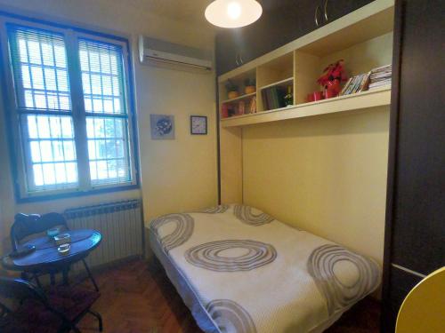 um pequeno quarto com uma pequena cama e uma mesa em Aprtman Sonja 2 em Belgrado