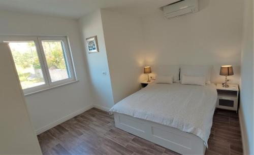 een witte slaapkamer met een bed en een raam bij ARIA in Sumartin