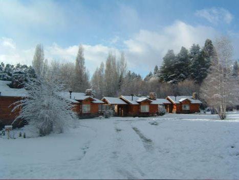 a group of wooden cabins in a snow covered yard at Cabañas En el Corazón del Bosque in San Carlos de Bariloche